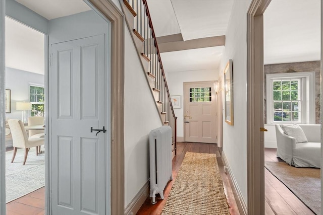 120 Court St, Dedham, MA 02026 - corridor featuring radiator heating unit, wood finished floors, healthy amount of natural light, and stairway