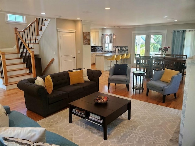 living room with light hardwood / wood-style flooring, ornamental molding, and sink