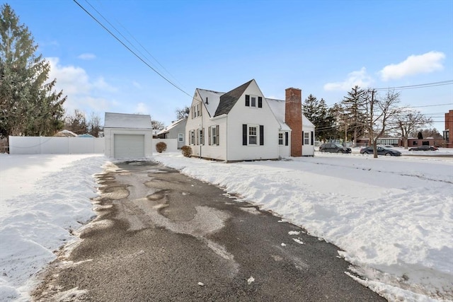 view of snow covered exterior featuring a garage and an outbuilding