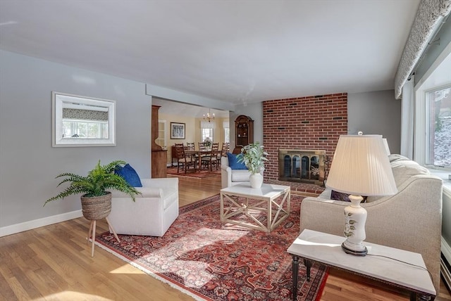 living room featuring a brick fireplace, plenty of natural light, and light hardwood / wood-style floors