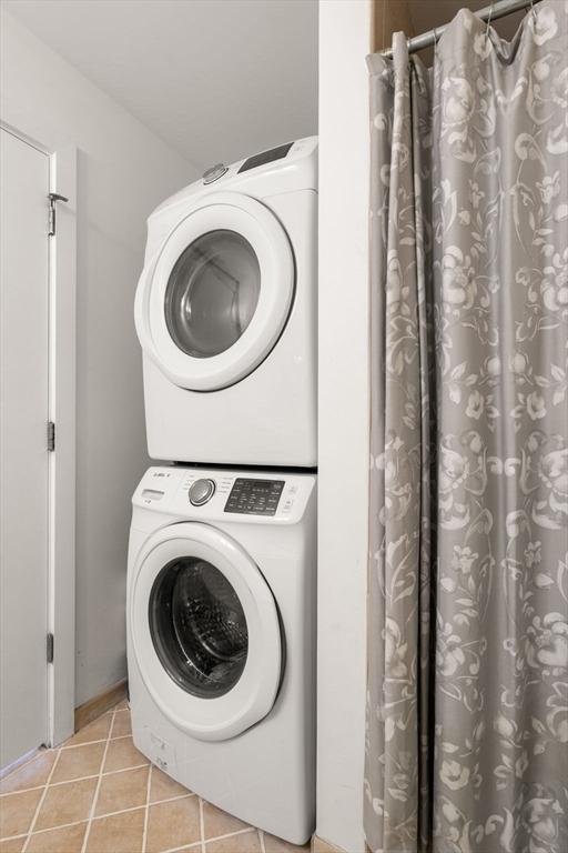 99 Chestnut Hill Ave Unit 212, Boston, MA 02135 - washroom featuring stacked washing machine and dryer and light tile patterned floors