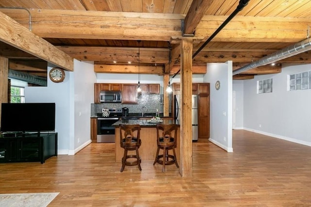 kitchen featuring appliances with stainless steel finishes, wooden ceiling, dark countertops, a kitchen breakfast bar, and light wood finished floors