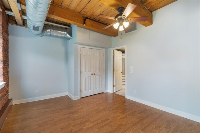 unfurnished bedroom with wooden ceiling, wood finished floors, beamed ceiling, baseboards, and a closet