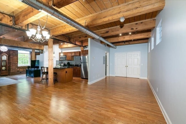 unfurnished living room featuring a chandelier, light wood-type flooring, beam ceiling, wooden ceiling, and baseboards