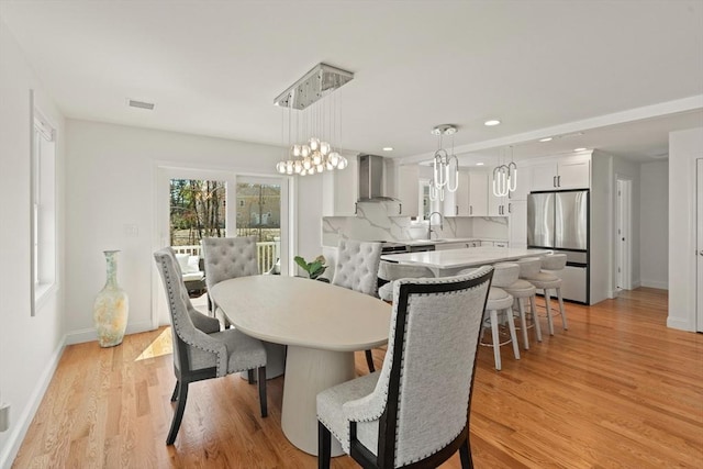 dining room with a notable chandelier, light wood finished floors, recessed lighting, baseboards, and visible vents