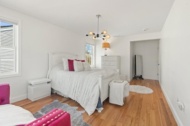 bedroom with baseboards, wood finished floors, and a chandelier