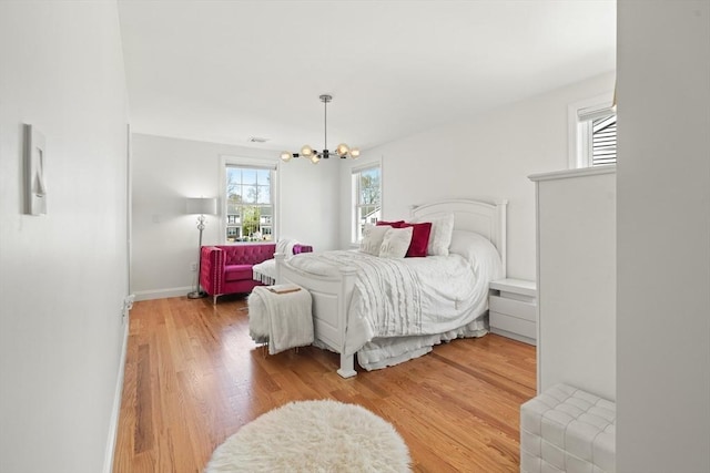 bedroom with an inviting chandelier, light wood-style floors, and baseboards