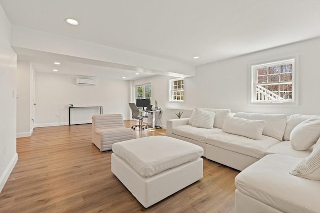 living area with baseboards, light wood-type flooring, an AC wall unit, and recessed lighting