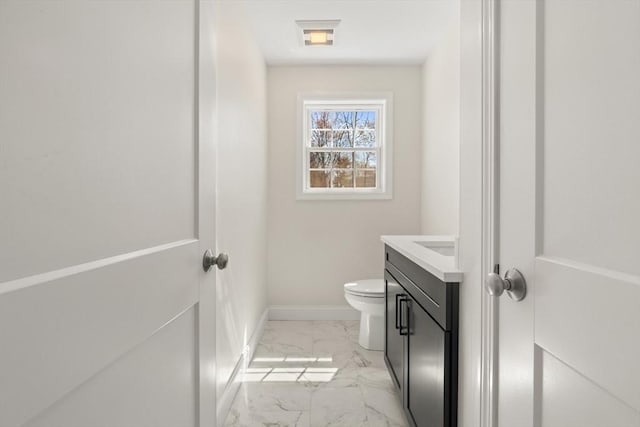 half bathroom with toilet, baseboards, marble finish floor, and vanity