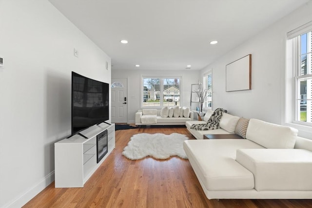 living room with recessed lighting, baseboards, and light wood-type flooring