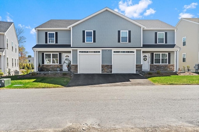 view of front of home featuring a garage, a front lawn, driveway, and stone siding