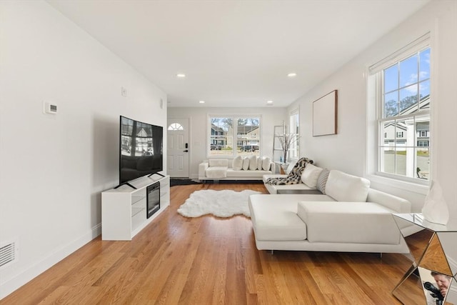 living room featuring recessed lighting, baseboards, light wood-type flooring, and a wealth of natural light