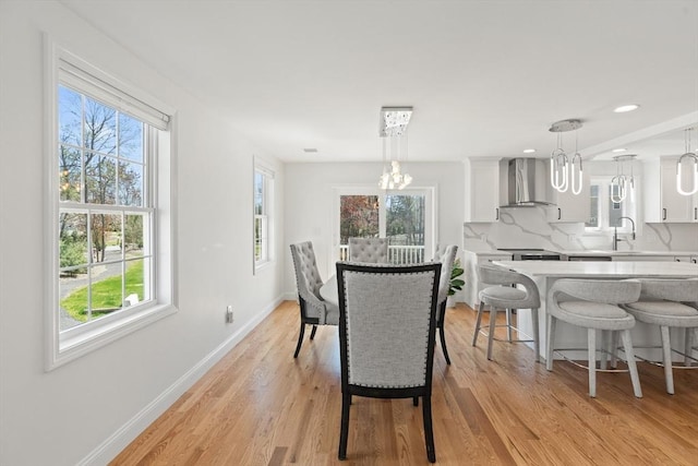 dining area with light wood-style floors, baseboards, a notable chandelier, and a healthy amount of sunlight