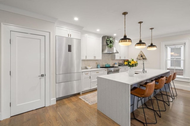 654 E 7th Unit 3, Boston, MA 02127 - kitchen featuring refrigerator, wall chimney range hood, white cabinetry, tasteful backsplash, and a kitchen island with sink