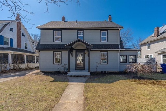 view of front of house with a chimney, a shingled roof, fence, and a front lawn