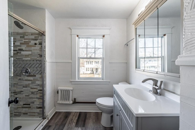 full bathroom featuring radiator, a shower stall, vanity, toilet, and wood finished floors