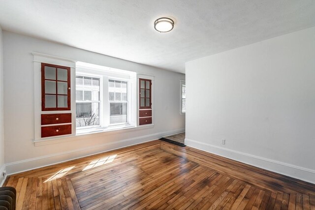 spare room with hardwood / wood-style flooring and baseboards