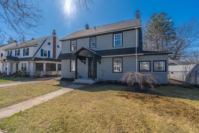view of front of home featuring roof with shingles, a front lawn, fence, and a chimney