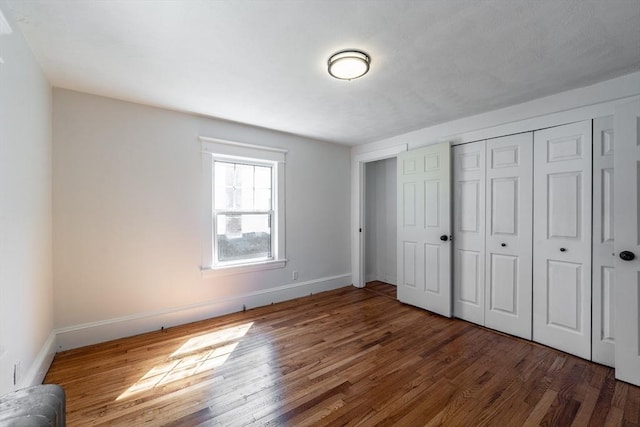 unfurnished bedroom with a closet, baseboards, and wood finished floors