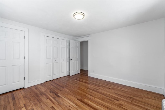 unfurnished bedroom with a closet, baseboards, and wood finished floors
