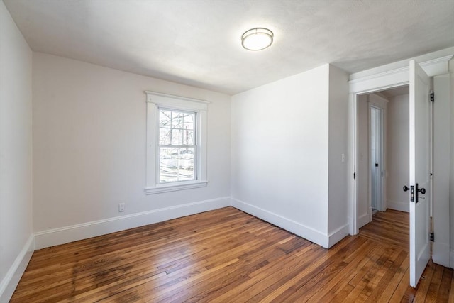 spare room with wood-type flooring and baseboards