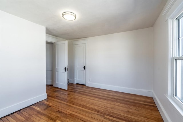 spare room featuring baseboards, plenty of natural light, and wood finished floors