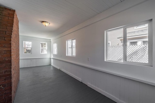empty room featuring wainscoting and dark wood finished floors