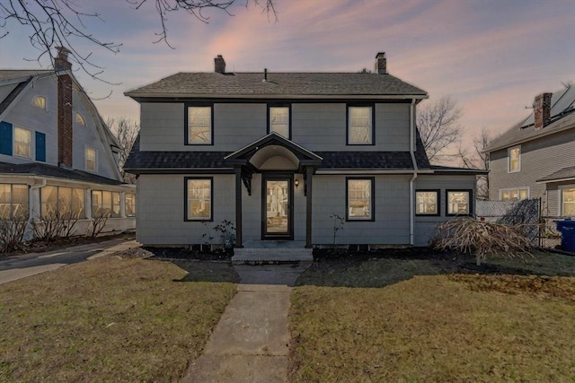 view of front of property featuring roof with shingles, a chimney, fence, and a lawn