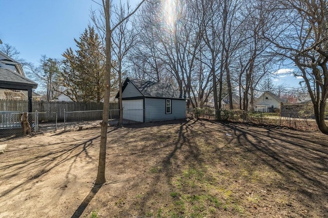 view of yard with a fenced backyard, a detached garage, and an outdoor structure