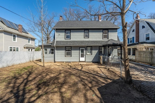 rear view of property with roof with shingles, a chimney, and a fenced backyard