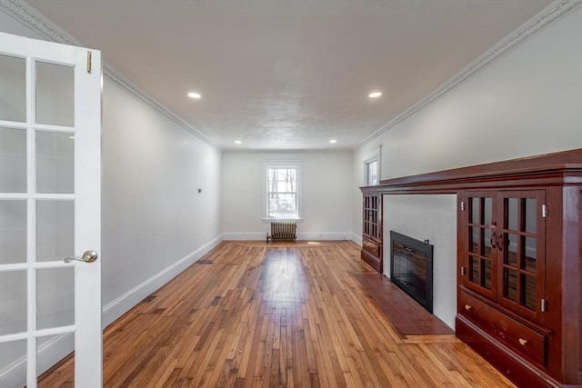 unfurnished living room featuring baseboards, crown molding, recessed lighting, hardwood / wood-style floors, and a tile fireplace