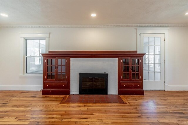unfurnished living room featuring recessed lighting, a fireplace, baseboards, and wood finished floors