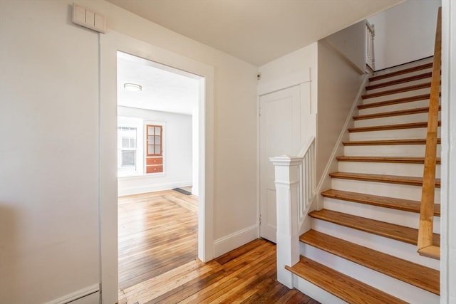 staircase featuring wood finished floors and baseboards