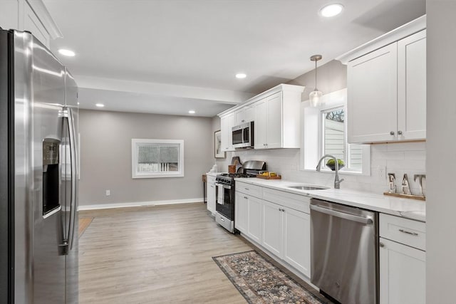 kitchen with stainless steel appliances, hanging light fixtures, sink, and white cabinets