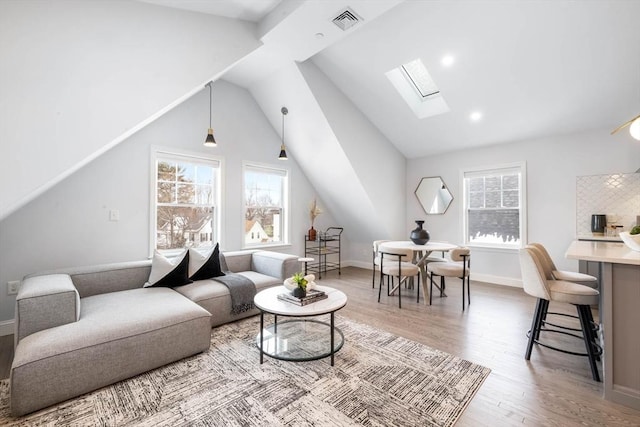 living room with vaulted ceiling with skylight and wood-type flooring