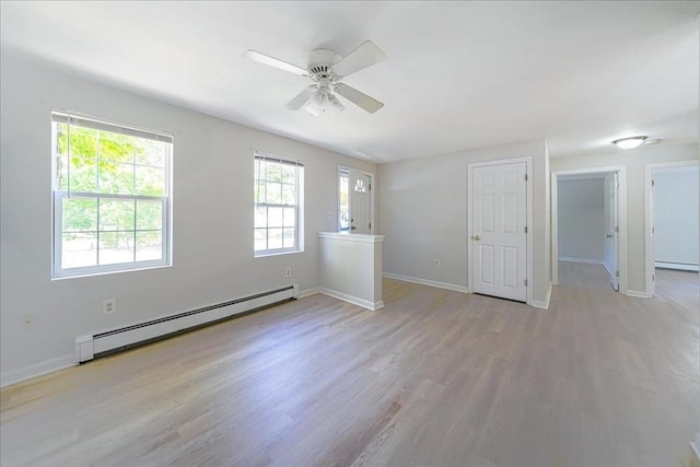 spare room featuring ceiling fan, baseboard heating, light wood-type flooring, and baseboards