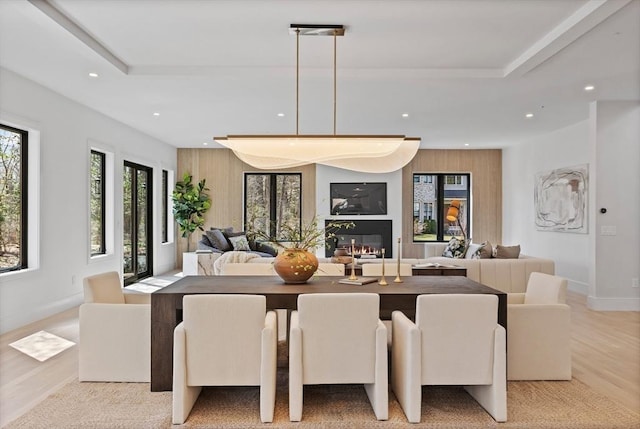 48 Sherburne Rd, Lexington, MA 02421 - dining room with recessed lighting, light wood-style flooring, a raised ceiling, a glass covered fireplace, and baseboards