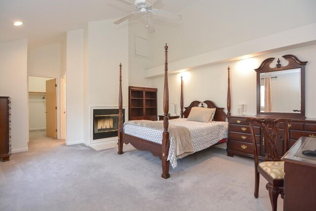 bedroom featuring a glass covered fireplace, baseboards, high vaulted ceiling, light colored carpet, and recessed lighting
