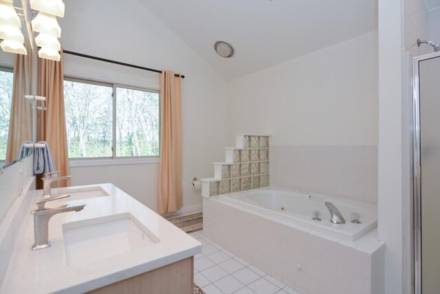 full bathroom featuring a whirlpool tub, tile patterned flooring, vaulted ceiling, and a wealth of natural light