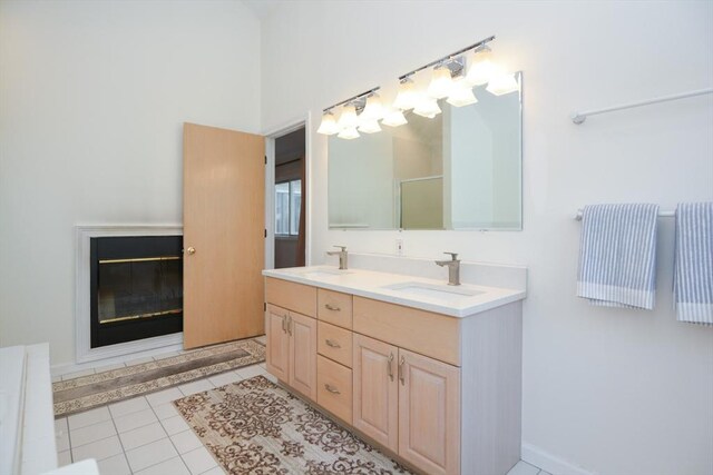 bathroom with double vanity, tile patterned flooring, a stall shower, a sink, and a glass covered fireplace