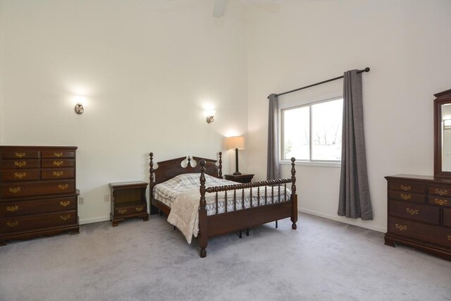 carpeted bedroom with baseboards, ceiling fan, and a towering ceiling