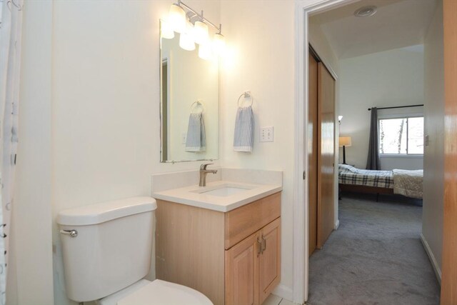 ensuite bathroom with vanity, connected bathroom, and toilet