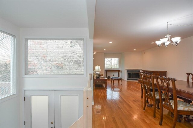 dining space with recessed lighting, light wood-style flooring, a chandelier, and a fireplace