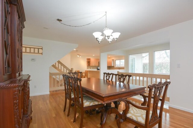 dining space featuring stairway, baseboards, a chandelier, and light wood finished floors