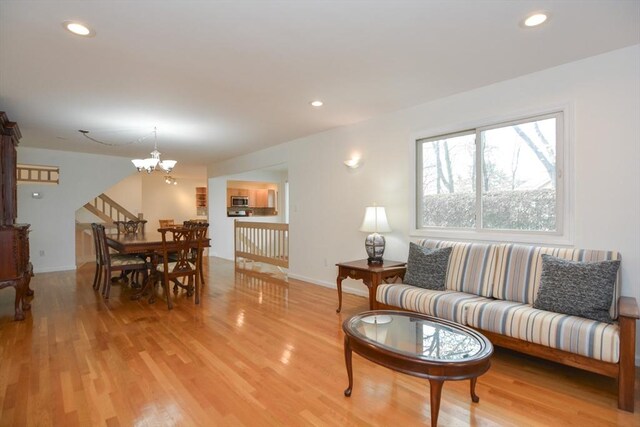 living room with an inviting chandelier, stairs, baseboards, recessed lighting, and light wood-type flooring