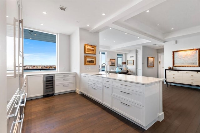 kitchen featuring wine cooler, a peninsula, a sink, dark wood-type flooring, and light countertops