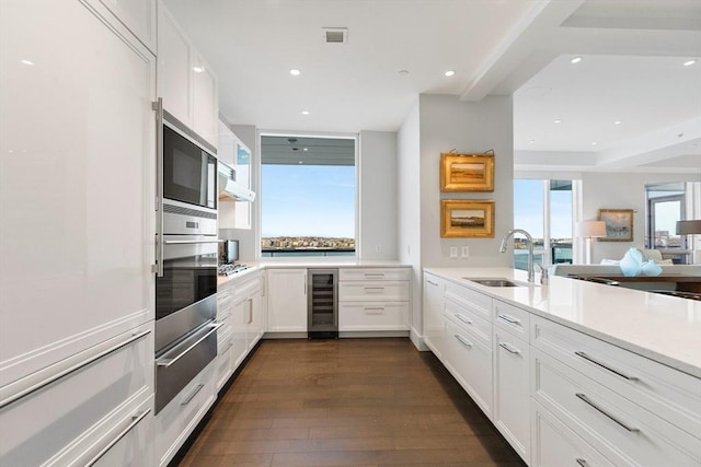 kitchen featuring a sink, beverage cooler, a warming drawer, stainless steel appliances, and dark wood-type flooring