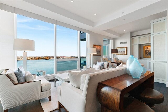 living area featuring dark wood-type flooring, a water view, and recessed lighting