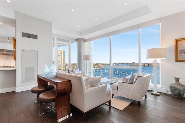 living area featuring dark wood-type flooring, baseboards, recessed lighting, and a water view