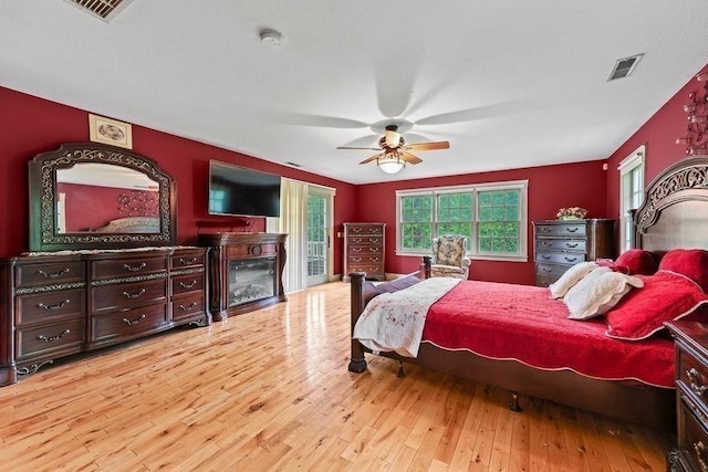 311 River Rd, South Hadley, MA 01075 - bedroom with hardwood / wood-style flooring, access to outside, a glass covered fireplace, and a ceiling fan